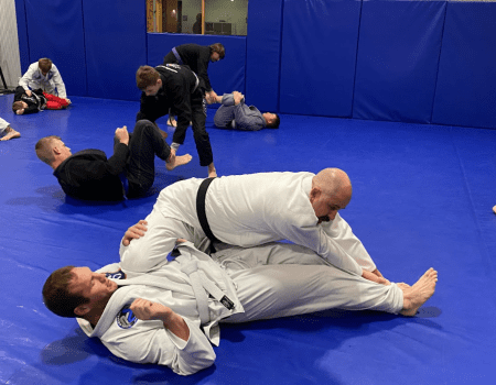 Adults practicing Brazilian Jiu-Jitsu in a dojo, showcasing training and techniques in adult Brazilian Jiu-Jitsu classes.