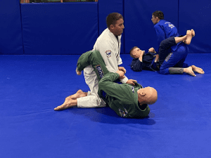 Adults Brazilian Jiu-Jitsu class practicing grappling techniques on the mat, highlighting adult Brazilian Jiu-Jitsu training.