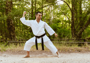 Man practicing judo in a forest, showcasing the discipline and skill required to achieve a black belt in martial arts.