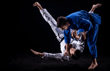 Judo athletes demonstrate a throw, showing the physical and mental benefits of judo training.