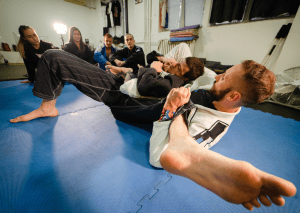 The BJJ instructor demonstrated a submission technique to students, with everyone focused on learning the move.