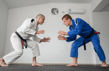 Two BJJ practitioners in a standing face-off, demonstrating ready stances and BJJ positions during training.