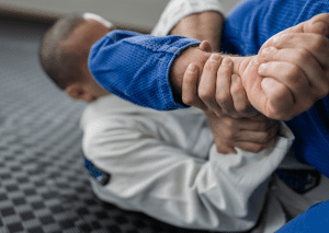 Close-up of a BJJ practitioner securing an armbar submission, focusing on grip strength and precise technique.