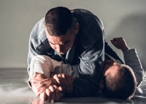 BJJ practitioner in the side control position, applying pressure and securing arm control for a submission setup.