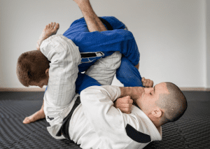 BJJ practitioners engaged in a grappling exchange, with one applying a triangle choke from the guard position.