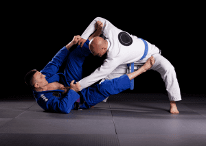 BJJ practitioners engaged in a complex guard position, with one attempting a sweep and the other maintaining balance.