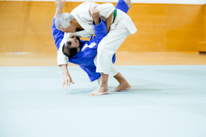 Two judo practitioners demonstrated judo takedowns on the mat, with one performing a throw on the other during training.