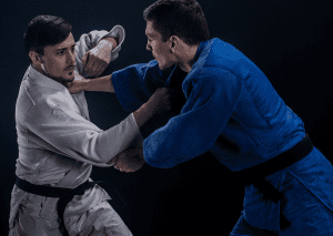 Two judo practitioners in gis engaging in a gripping fight, demonstrating technique and focus during a training session.