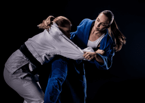 Two women in judo gi practicing grappling techniques during a judo training session, demonstrating strength and skill.