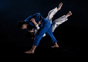 Two judokas execute a powerful throw on a dark background, showcasing the dynamic motion and technique of judo.