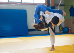 Two judo practitioners demonstrated judo takedowns on the mat, with one executing a throw on the other during practice.