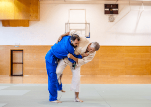 Two judo practitioners demonstrated judo takedowns on the mat, with one executing a throw on the other during training.