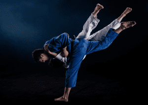 Two judo practitioners in gis performing a high-impact throw, captured in mid-air during a dynamic training session.