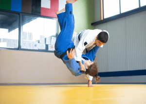 Two judo practitioners in gis performing a throw during training, with one in mid-air and the other executing the technique.