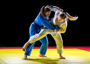 Two female judo practitioners in gis performing a throw on the mat, demonstrating strength and technique during training.