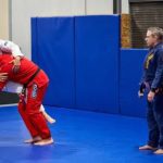 Instructors demonstrating grappling techniques in self-defense classes at a martial arts gym.