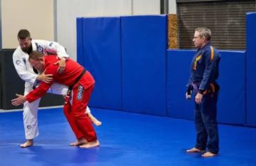 Instructors demonstrating grappling techniques in self-defense classes at a martial arts gym.