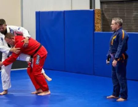 Instructors demonstrating grappling techniques in self-defense classes at a martial arts gym.