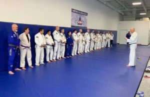 Students lined up for self-defense classes in martial arts uniforms, receiving instructions from an experienced instructor.