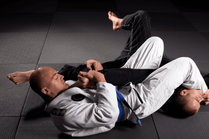 Two men practicing Brazilian jiu-jitsu on the mat, with one applying an armbar submission on the other.